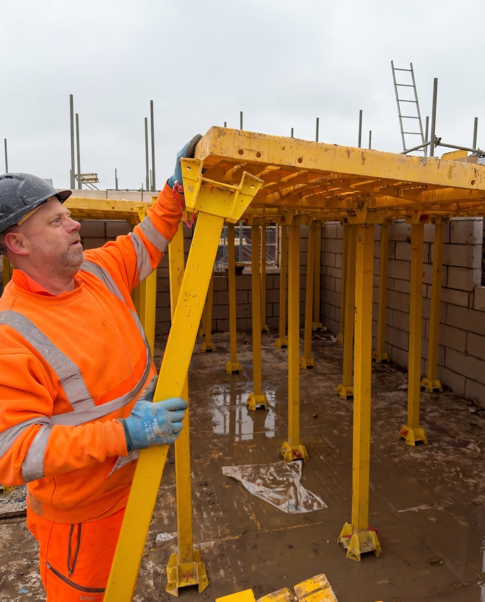 Operative in hi-vis fitting a yellow Trad Deck leg and beam beneath the platform