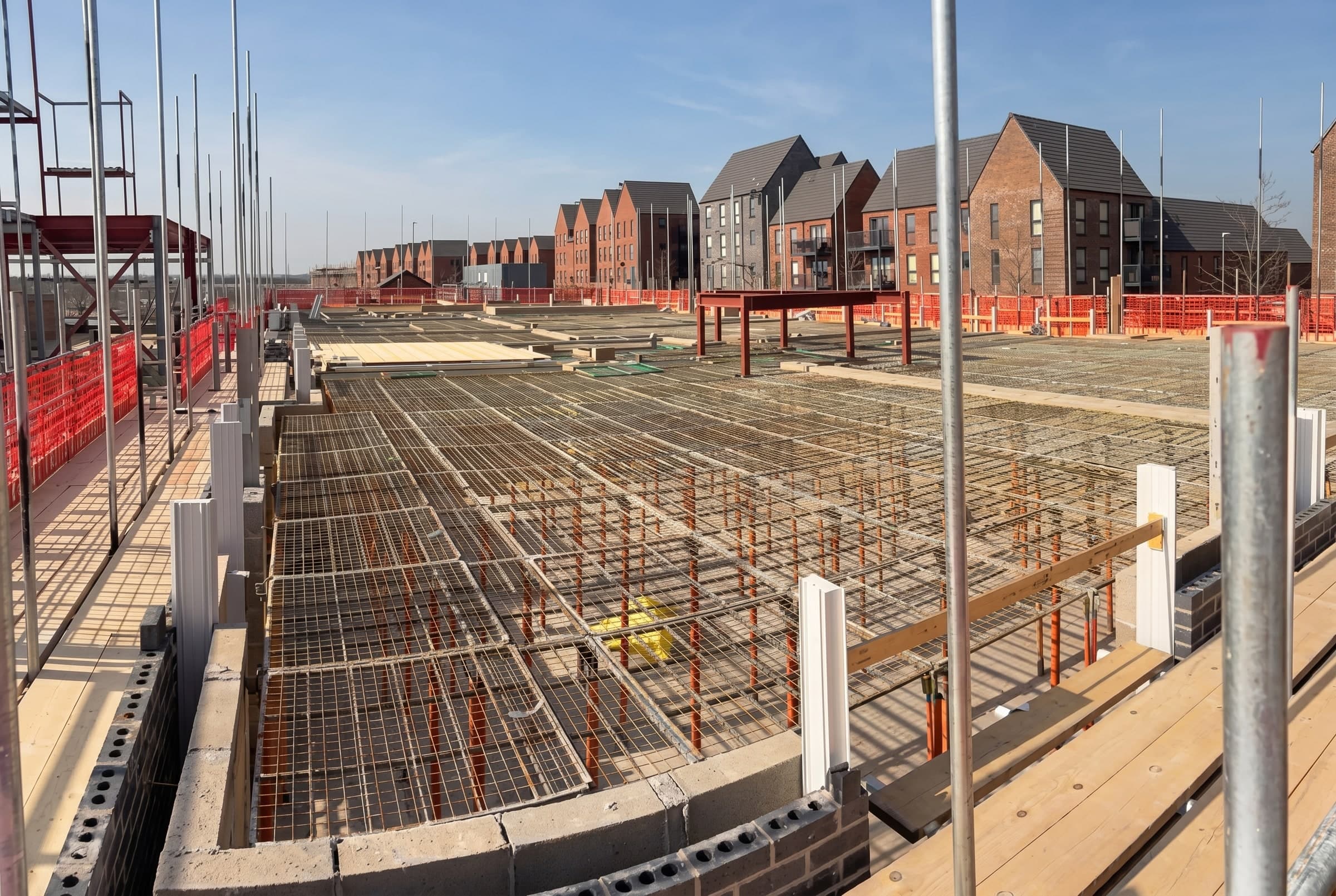 G-Deck Lite steel mesh safety decking across a large floor plate, new homes beyond