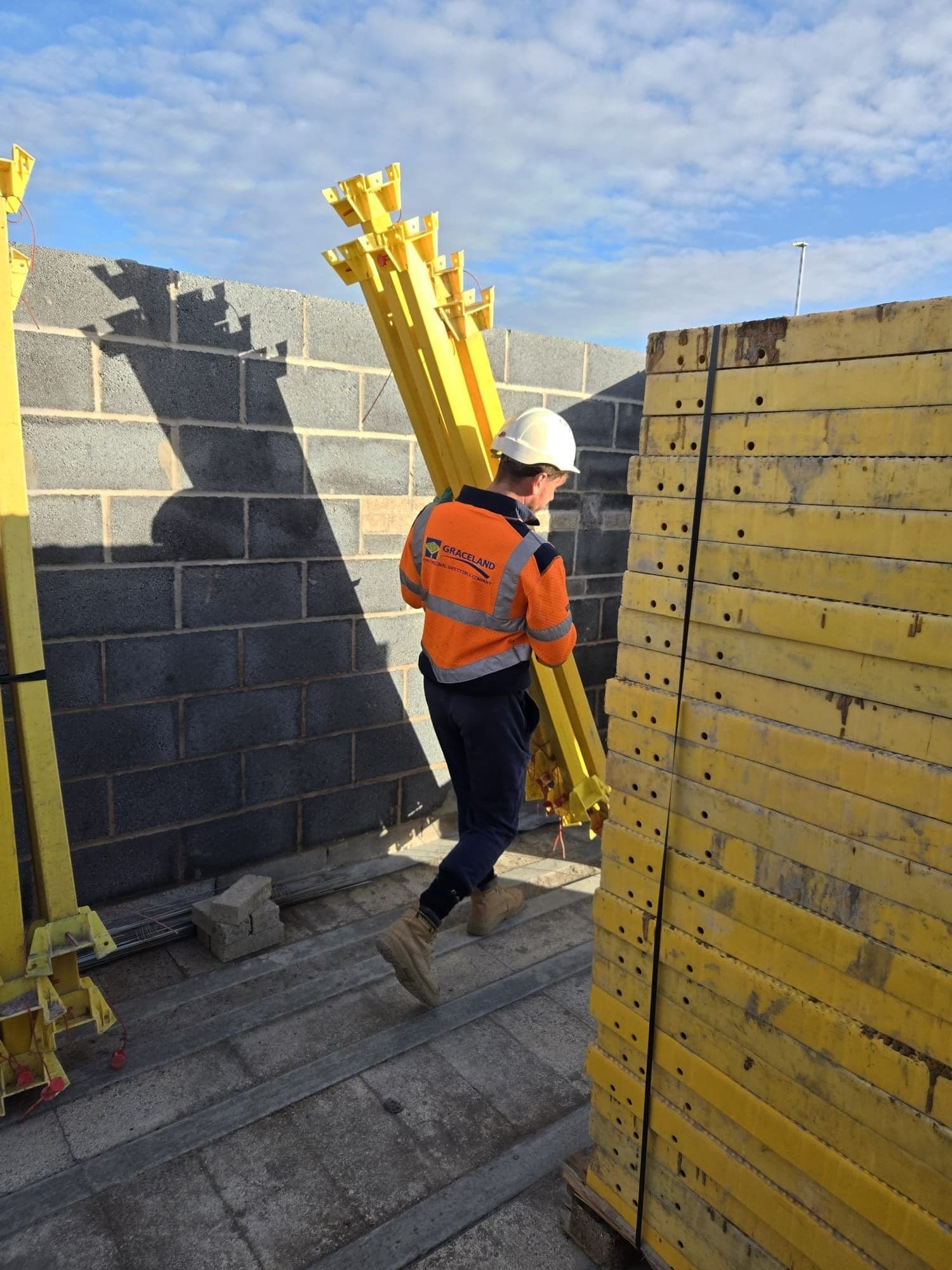 Graceland operative carrying Trad Deck leg units on an upper floor, crane beyond